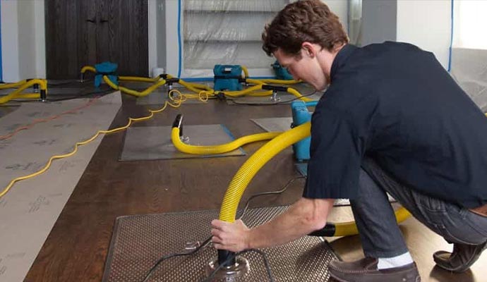 Worker using water damage restoration equipment